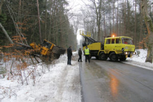 Śnieżna droga z przejeżdżającą obok żółtą ciężarówką.