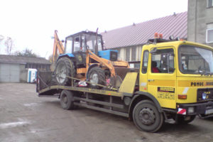 Galeria zdjęć żółtej ciężarówki z traktorem z tyłu.