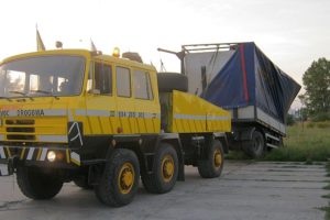 Żółta ciężarówka z niebieską plandeką jest prezentowana w galerii zdjęć.